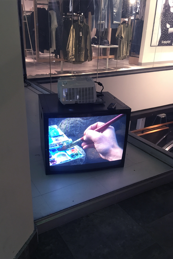 A monitor that shows a hand and a watercolor box